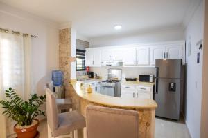 a kitchen with white cabinets and a stainless steel refrigerator at MB Apartment - A in San Felipe de Puerto Plata
