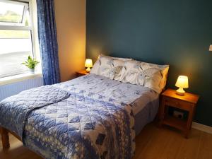 a bedroom with a bed and two lamps on tables at Woodmount Cottage in Ennistymon