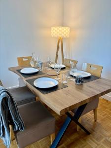 a wooden table with plates and wine glasses on it at Le Carré Chic in Limoges