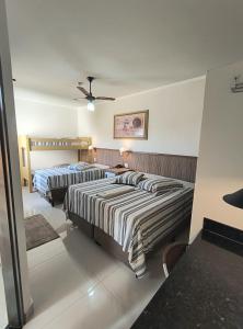 a bedroom with two beds and a ceiling fan at Hotel Graunas in São Carlos
