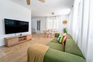 a living room with a green couch and a flat screen tv at Comfortable & Spacious Mountain Home in Utuado in Cayuco