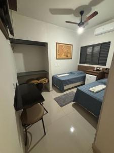 a bedroom with two beds and a table and chairs at Hotel Graunas in São Carlos