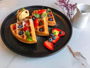 a black plate of waffles with fruit and ice cream at Hotel Lince in Lima