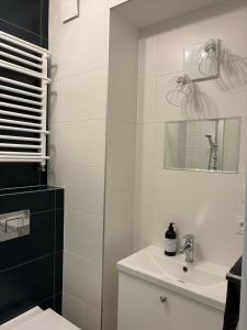 a white bathroom with a sink and a mirror at Panda Apartment Plac Solny 4 z klimatyzacją in Głogów