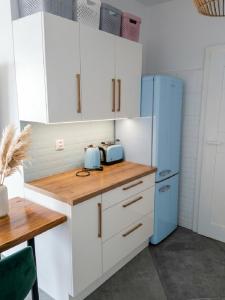 a kitchen with white cabinets and a blue refrigerator at Apartament na Bora in Tarnów