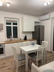 a kitchen with a white table and chairs and a kitchen with a refrigerator at Panda Apartment Plac Solny 4 z klimatyzacją in Głogów +6 photos