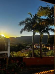 two palm trees on top of a house with the sunset at Casa Flamboiam in Tiradentes
