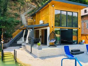 a house with a swing and some blue chairs at Lake house Emerald in Jablanica