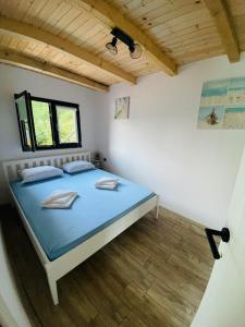 a bedroom with a bed with blue sheets and a window at Lake house Emerald in Jablanica