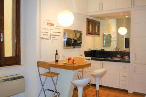 ローマにあるNavona Secret Suiteの白いキャビネット、テーブルと椅子付きのキッチンが備わります。