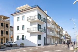 a white building with balconies on a street at Affittacamere Prima Fila Mare in Porto Recanati