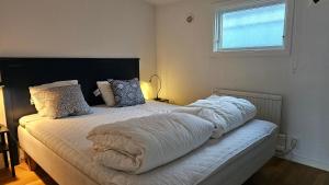 ein Schlafzimmer mit einem Bett mit weißer Bettwäsche und einem Fenster in der Unterkunft Real holiday feeling with sauna in Beddinge Strand