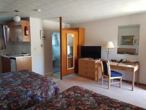 a hotel room with a bed and a desk with a computer at Alberni Inn in Port Alberni