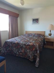 a hotel room with a bed with a floral bedspread at Alberni Inn in Port Alberni +2 photos