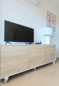 a flat screen tv sitting on top of a wooden cabinet at Charli beach in Miramar