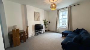 a living room with a blue couch and a television at The Teign Rooms in Teignmouth