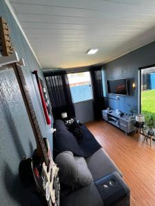 a living room with a couch and a guitar at 4 min do Paraguai Casa com piscina e privacidade in Foz do Iguaçu