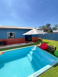 a swimming pool with an umbrella next to a house at 4 min do Paraguai Casa com piscina e privacidade in Foz do Iguaçu