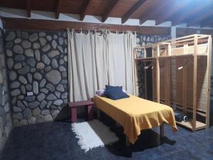 a bedroom with a bed and a stone wall at Casa El molinito in Chilecito