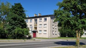 a large brick building with a red door on a street at Central Haapsalu Apartment in Haapsalu