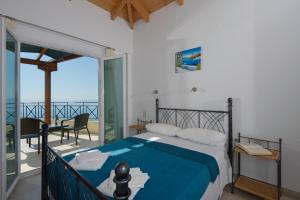 a bedroom with a bed and a balcony with the ocean at Eleonora Villa in Évyiros