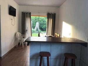 a kitchen with a counter and two stools in a room at Riba House in Imbituba