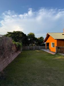 an orange house in a yard next to a fence at Riba House in Imbituba +7 photos