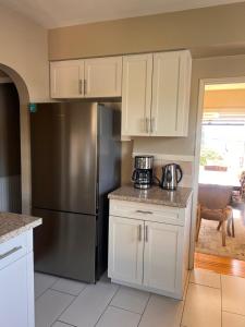 a kitchen with white cabinets and a stainless steel refrigerator at Sunset Ocean Retreat in West Vancouver