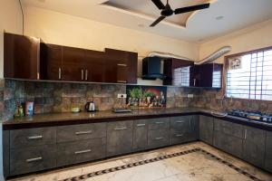 a kitchen with brown cabinets and a ceiling fan at Kubn Retreat in Chandigarh Airport