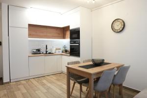 a kitchen with a wooden table and a clock on the wall at StarLux Residence - Because you deserve it! in Ćuprija +10 photos