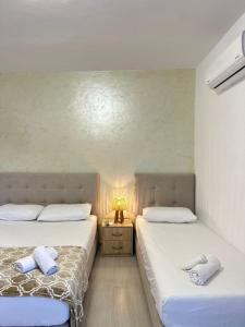 two beds in a bedroom with a lamp on a night stand at Villa Adi Saranda in Sarandë