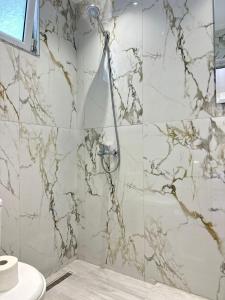 a shower in a bathroom with a marble wall at Villa Adi Saranda in Sarandë