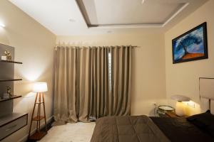 a bedroom with a bed and a window with curtains at 2Kubn retreat in Chandigarh Airport