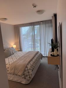 a bedroom with a bed and a large window at Beach Getaway in Mount Maunganui +11 photos