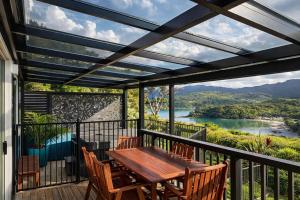 a patio with a wooden table and chairs on a balcony at Coromandel Seaview Motel in Coromandel Town