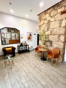 a living room with a stone wall and chairs and a table at Hotel The Cathedral Vegueta in Las Palmas de Gran Canaria