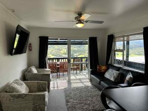 a living room with a couch and chairs and a tv at Coromandel Seaview Motel in Coromandel Town