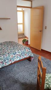 a bedroom with a bed and a door and a chair at La Salvaje Bazar Mágico in Yucay