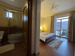 a bedroom with a bed and a bathroom with a window at Котедж в ГОРАХ in Solochyn