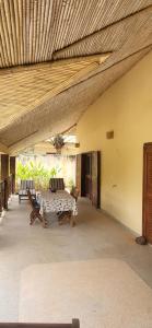 a patio with a table and chairs and a ceiling at Belle maison dans résidence avec piscine in Cap Skirring