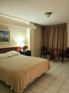 a hotel room with a bed and a table and chairs at Hotel Estrella in Managua +35 photos