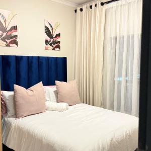 a bed with white sheets and pillows next to a window at Kurhula nest in Midrand