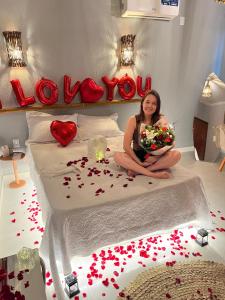 a woman sitting on a bed with flowers and hearts at Hotel Pousada Vila da Natureza in Maceió +27 photos