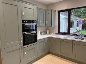 a kitchen with gray cabinets and a window and a sink at Whitepark Lodge in Lisnaskea