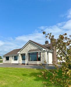 a white brick house with a grass yard at Whitepark Lodge in Lisnaskea