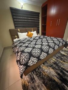 a bedroom with a bed with a black and white comforter at Max Heron in Ikeja