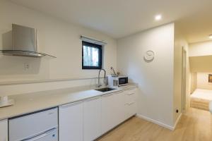 a white kitchen with a sink and a microwave at Modern King-Size Guest Suite with AC in Burnaby +7 photos