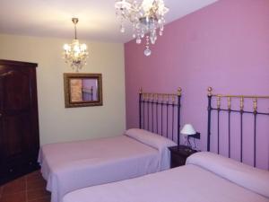 duas camas num quarto com paredes roxas em Casa Júnez em Romanillos de Medinaceli