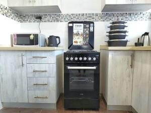a kitchen with a stove and a microwave at Laxury3BR Mins to Nyali Beach fast WiFi Netflix AC and Free Parking Near wild waters in Mombasa
