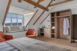a bedroom with a bed and a chair and a window at Bryggjan Boutique Hotel in Akureyri